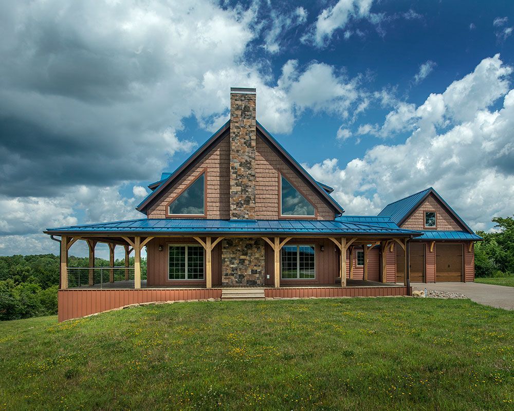 A large house with a blue roof is sitting on top of a grassy hill.