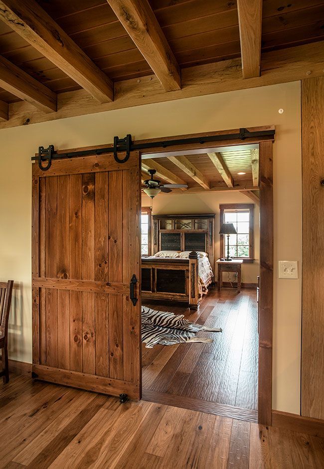 A bedroom with a sliding barn door leading to a bedroom.