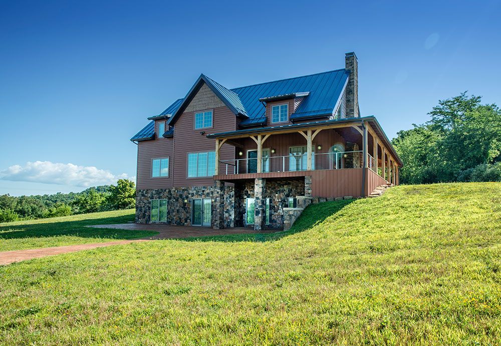 A large house is sitting on top of a grassy hill.