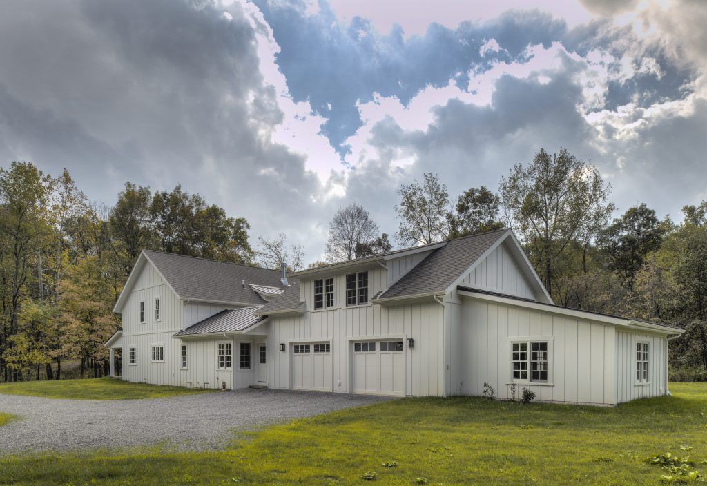 A large white house sits in the middle of a grassy field.