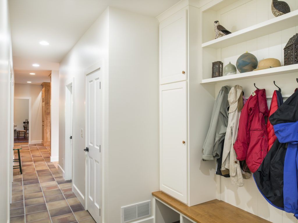 A hallway with a bench and coats hanging on the wall.