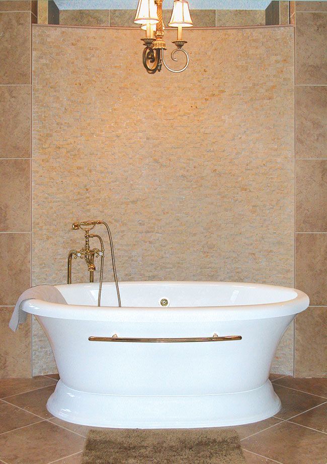 A bathtub in a bathroom with two lamps above it.