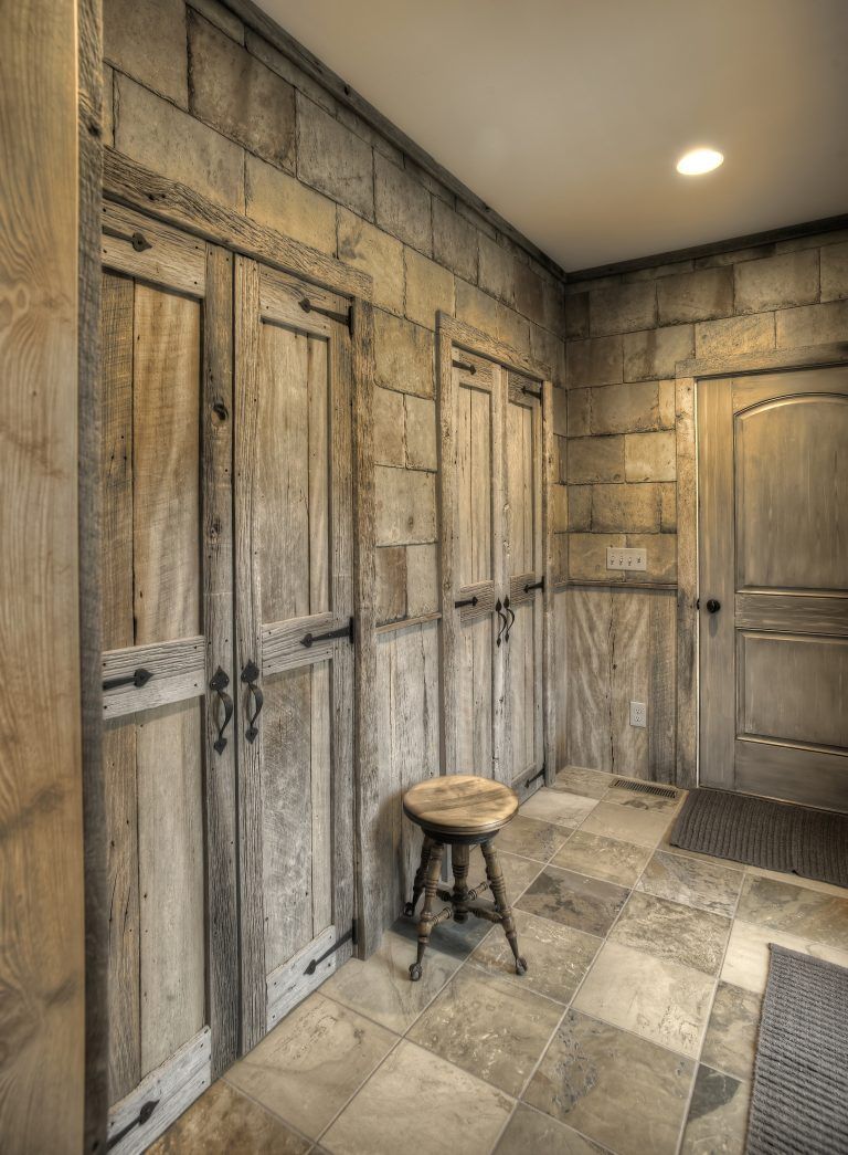 A hallway with wooden doors, wooden walls, and a wooden stool.