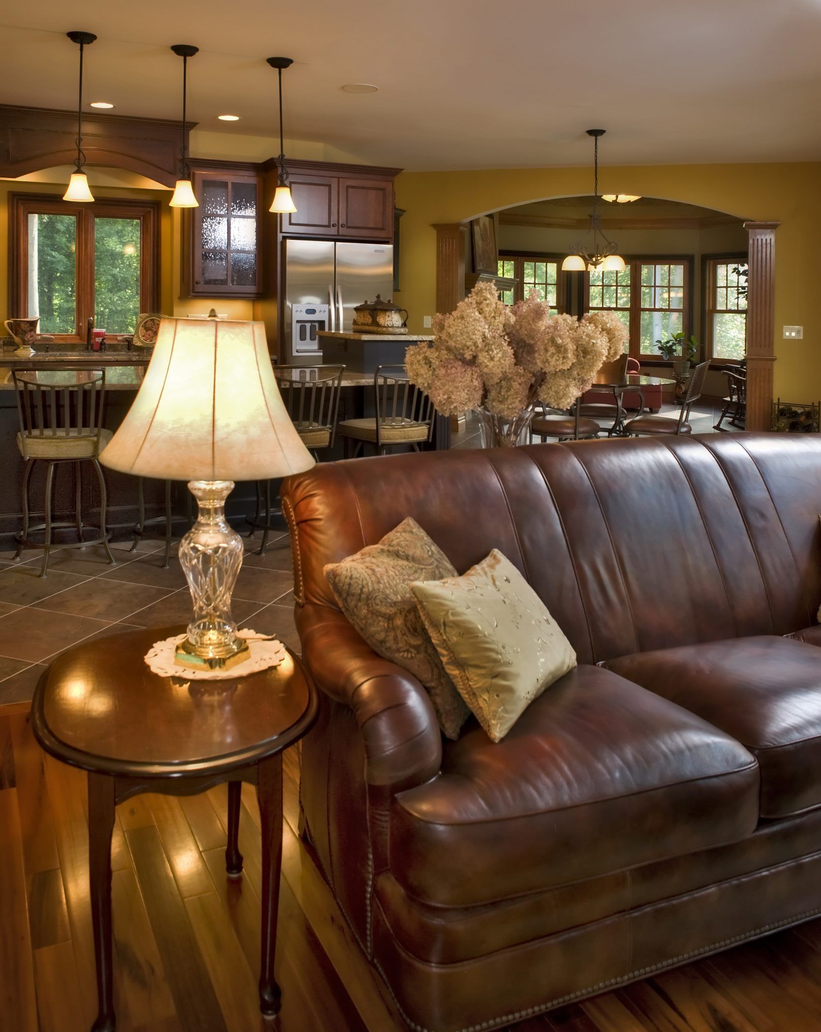 A living room with a brown leather couch and a lamp.