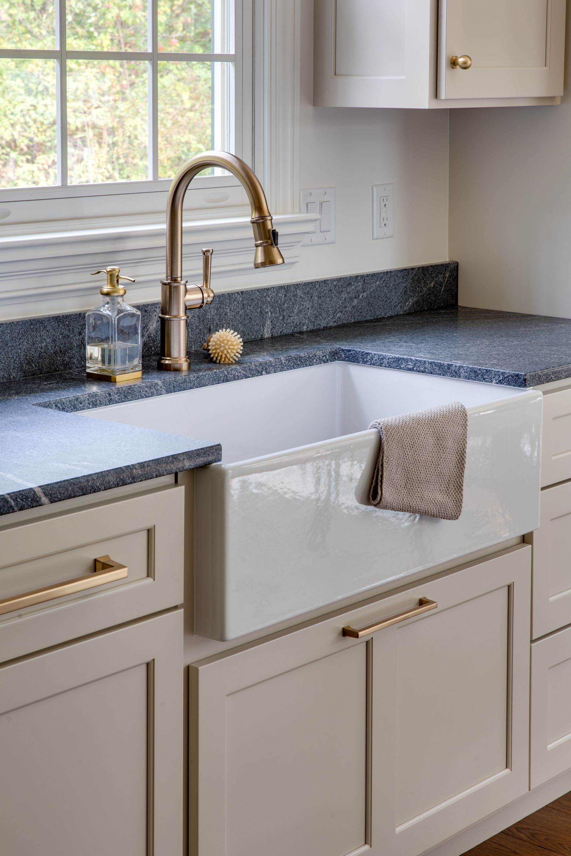 A kitchen with a sink , cabinets , and a window.