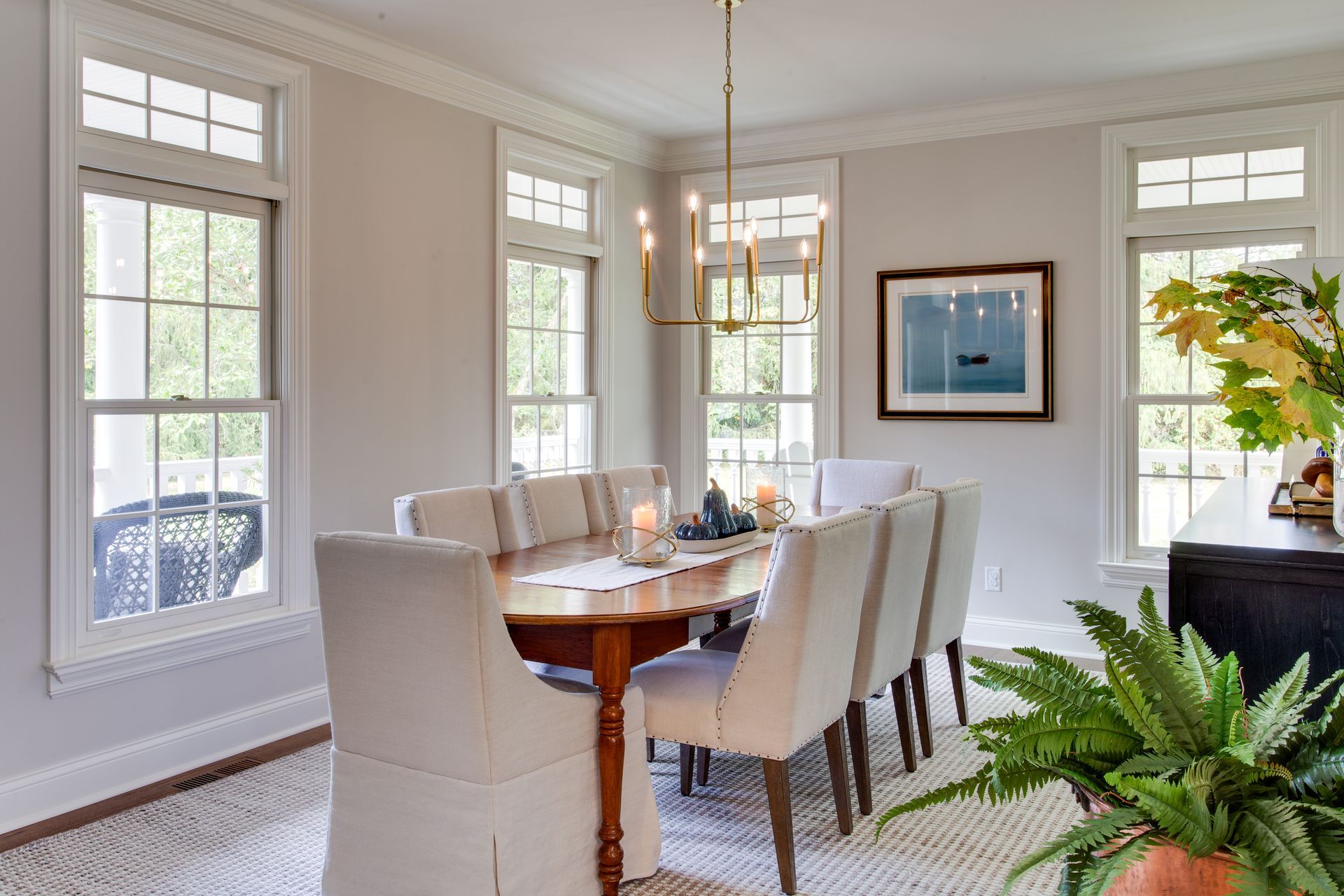 A dining room with a long table and chairs and a chandelier hanging from the ceiling.