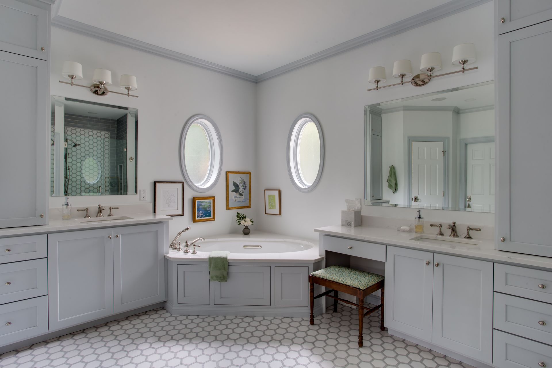 A bathroom with two sinks , a tub , two mirrors and a stool.