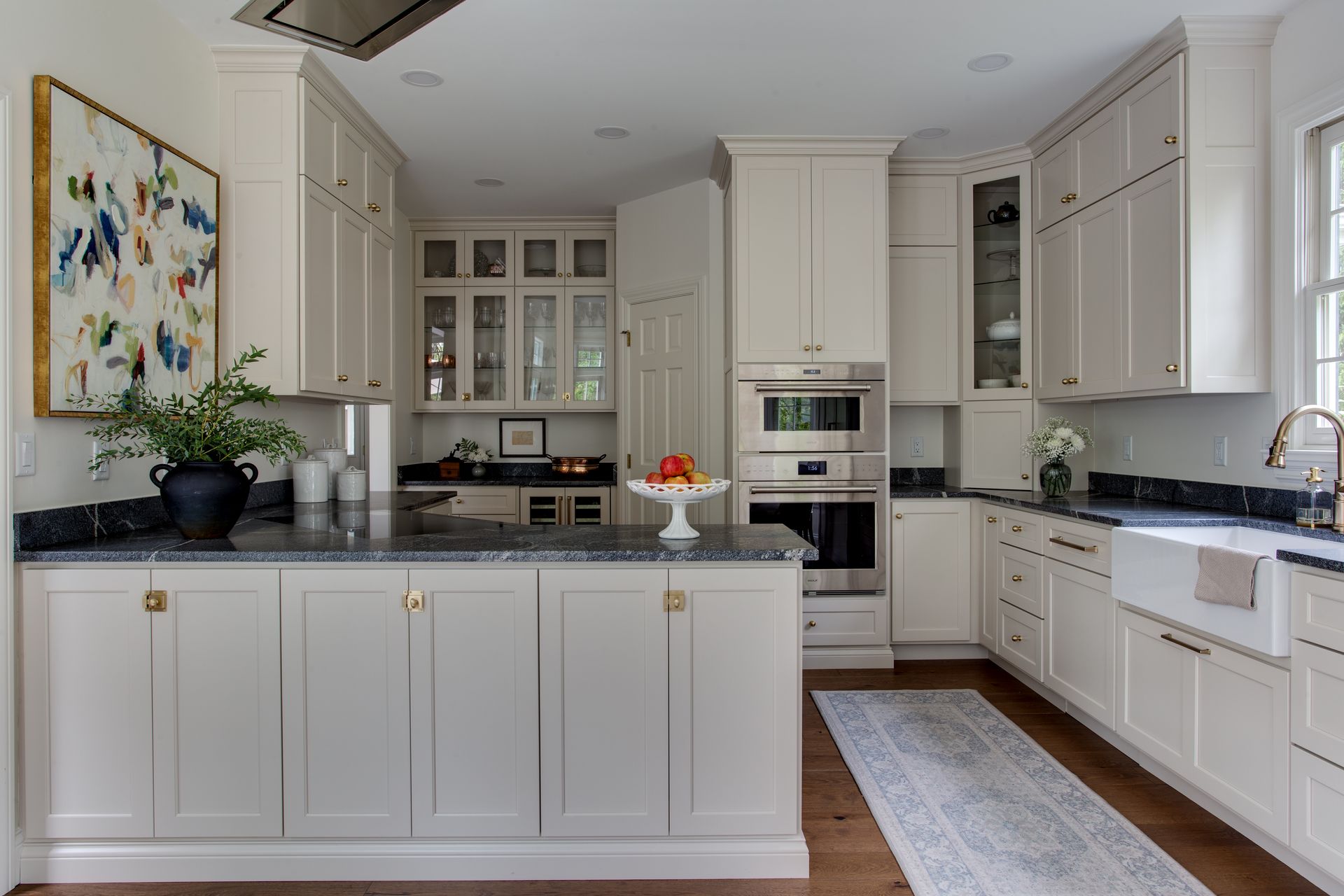 A kitchen with white cabinets and black counter tops.