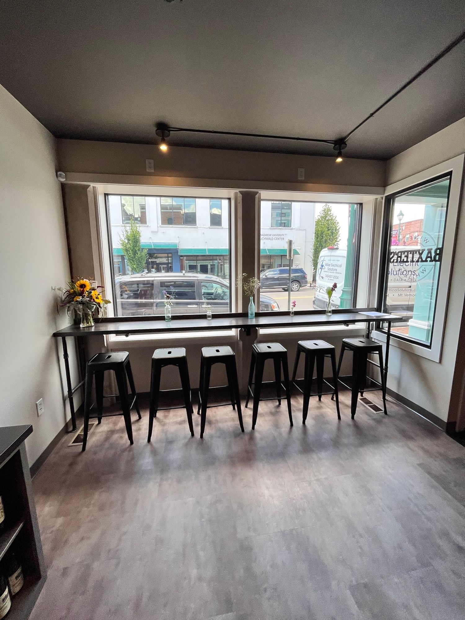 A room with tables and stools in front of a window.