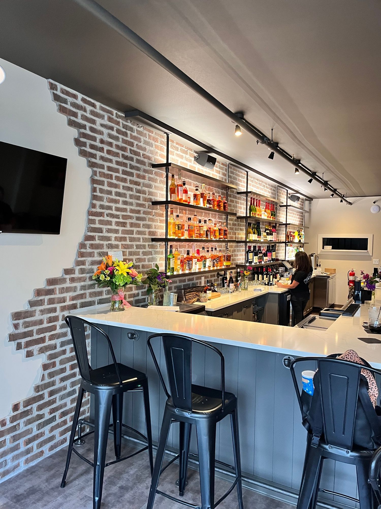A bar with a brick wall and a television on the wall.