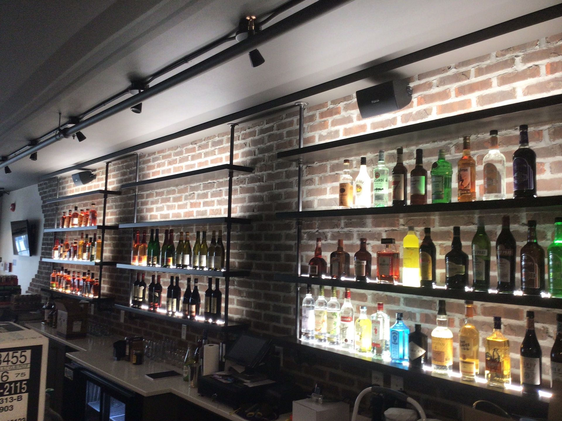 A bar with lots of bottles of liquor on shelves.