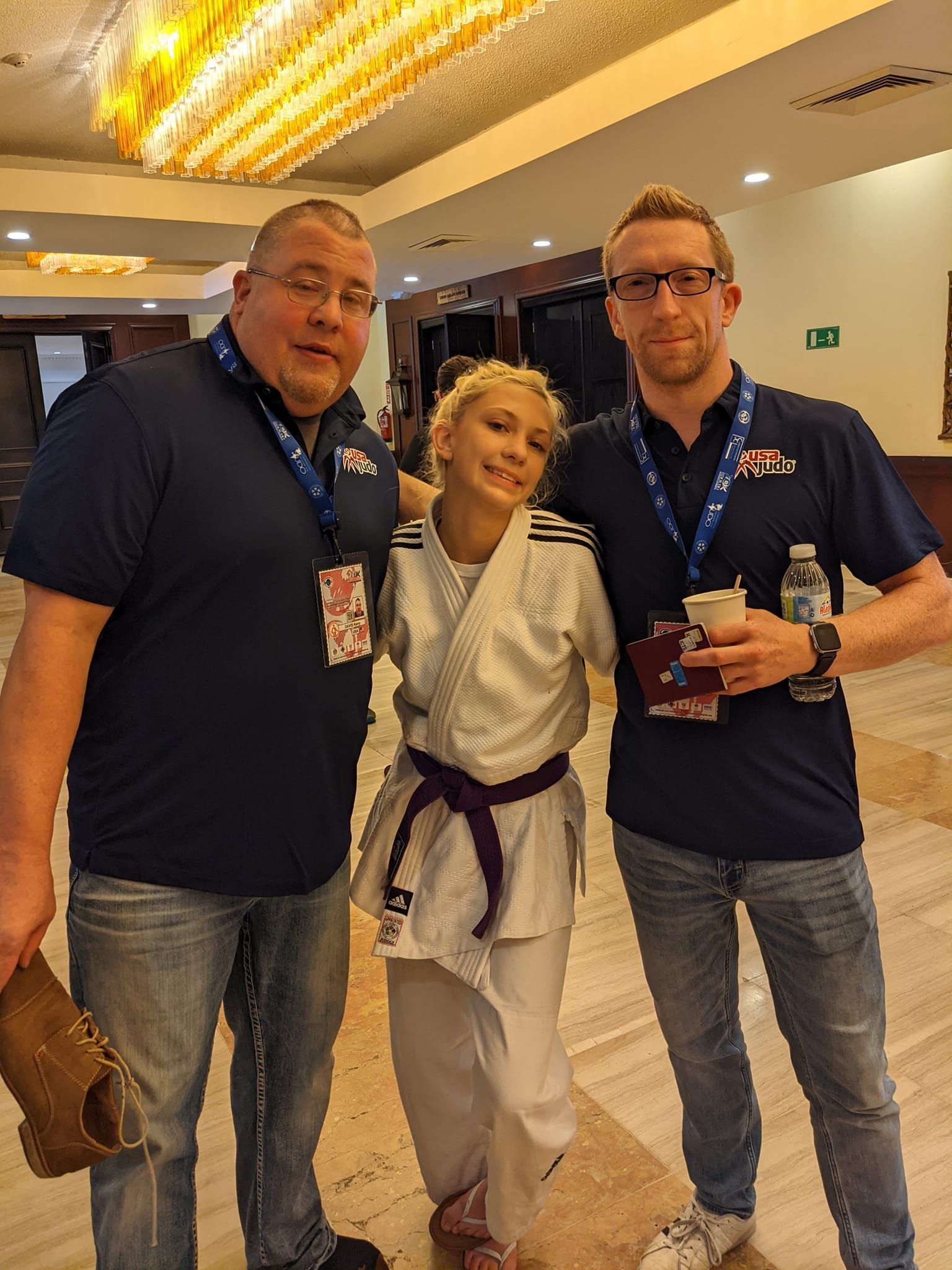 A woman in a karate uniform is posing for a picture with two men.