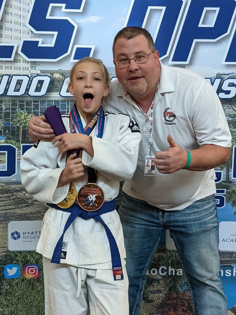 A man is standing next to a young girl in a judo uniform.