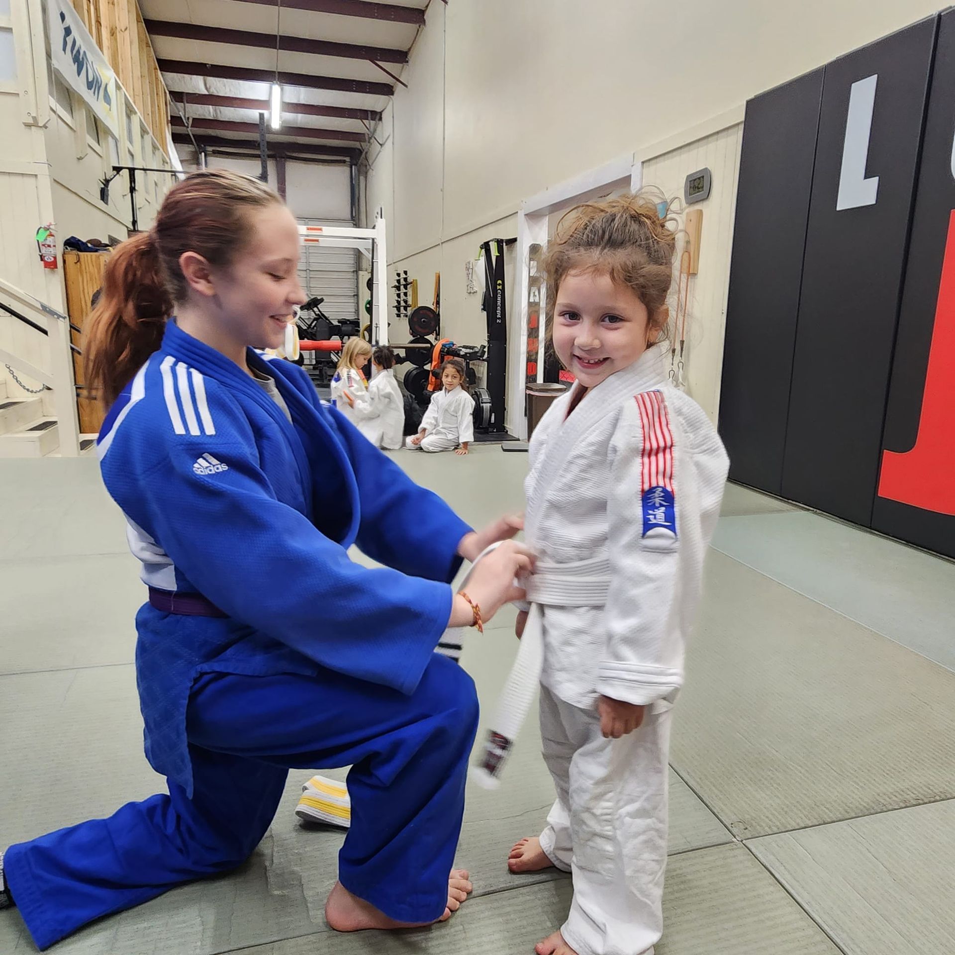 A woman in a blue kimono is kneeling down next to a young boy in a white kimono