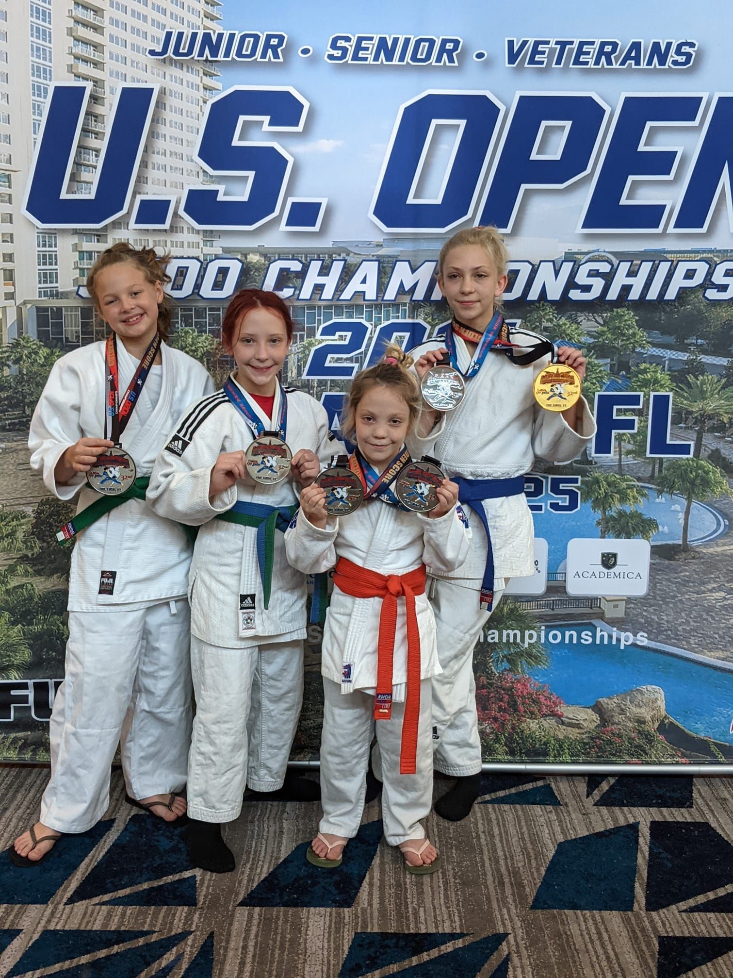 A group of young girls are standing in front of a sign that says u.s. open judo championships.