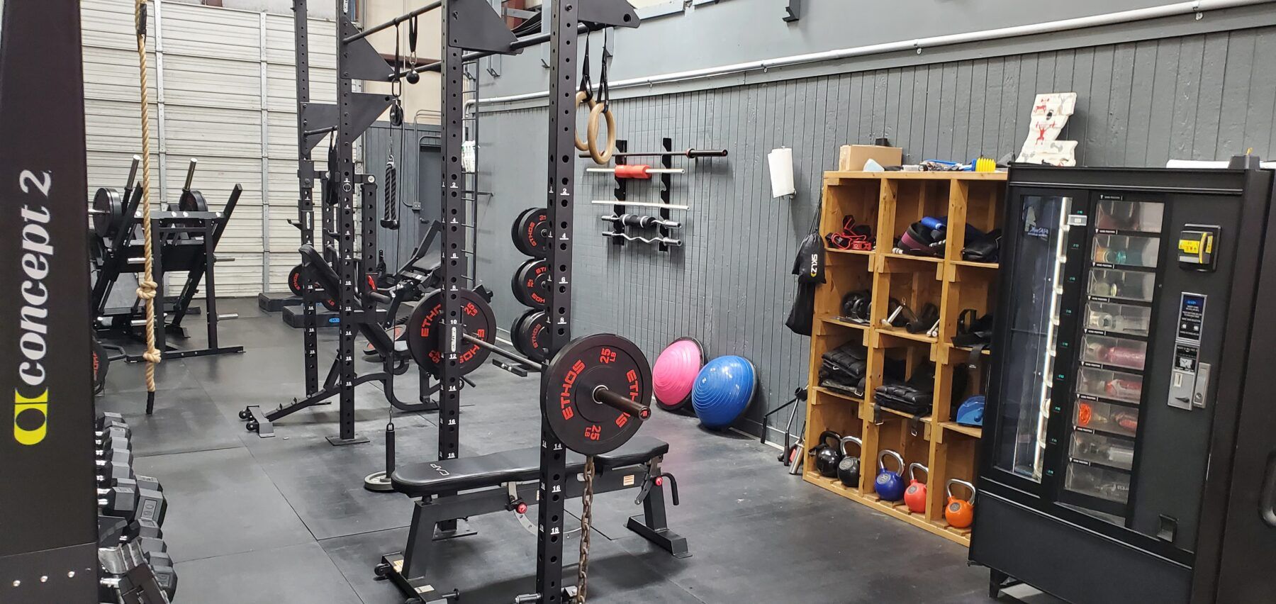 A gym with a lot of exercise equipment and a vending machine.