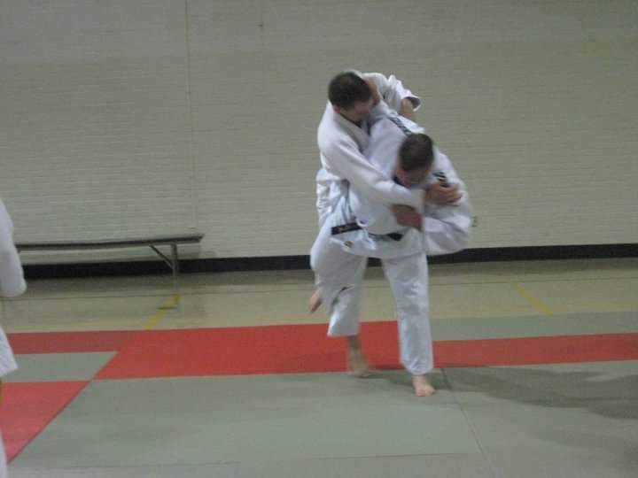 Two men are wrestling on a mat in a gym