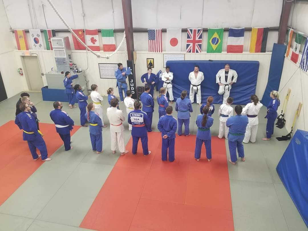 A group of people are standing in a room with flags on the wall.