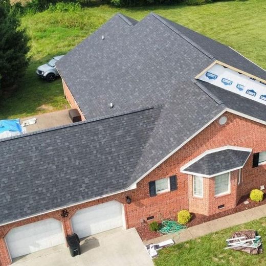 Brick house with brown garage door, small garden, and blue sky over a driveway