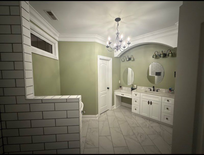 Spacious bathroom with green walls, white tile, vanity sinks, mirrors, and a chandelier ceiling light