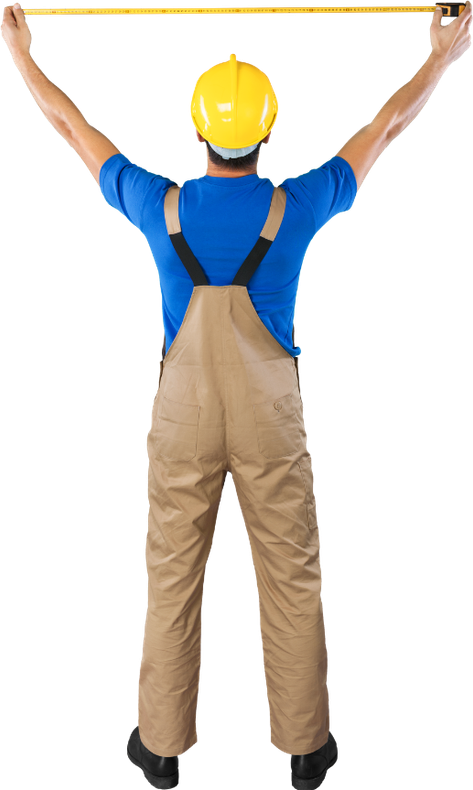 A man in overalls is measuring something with a tape measure