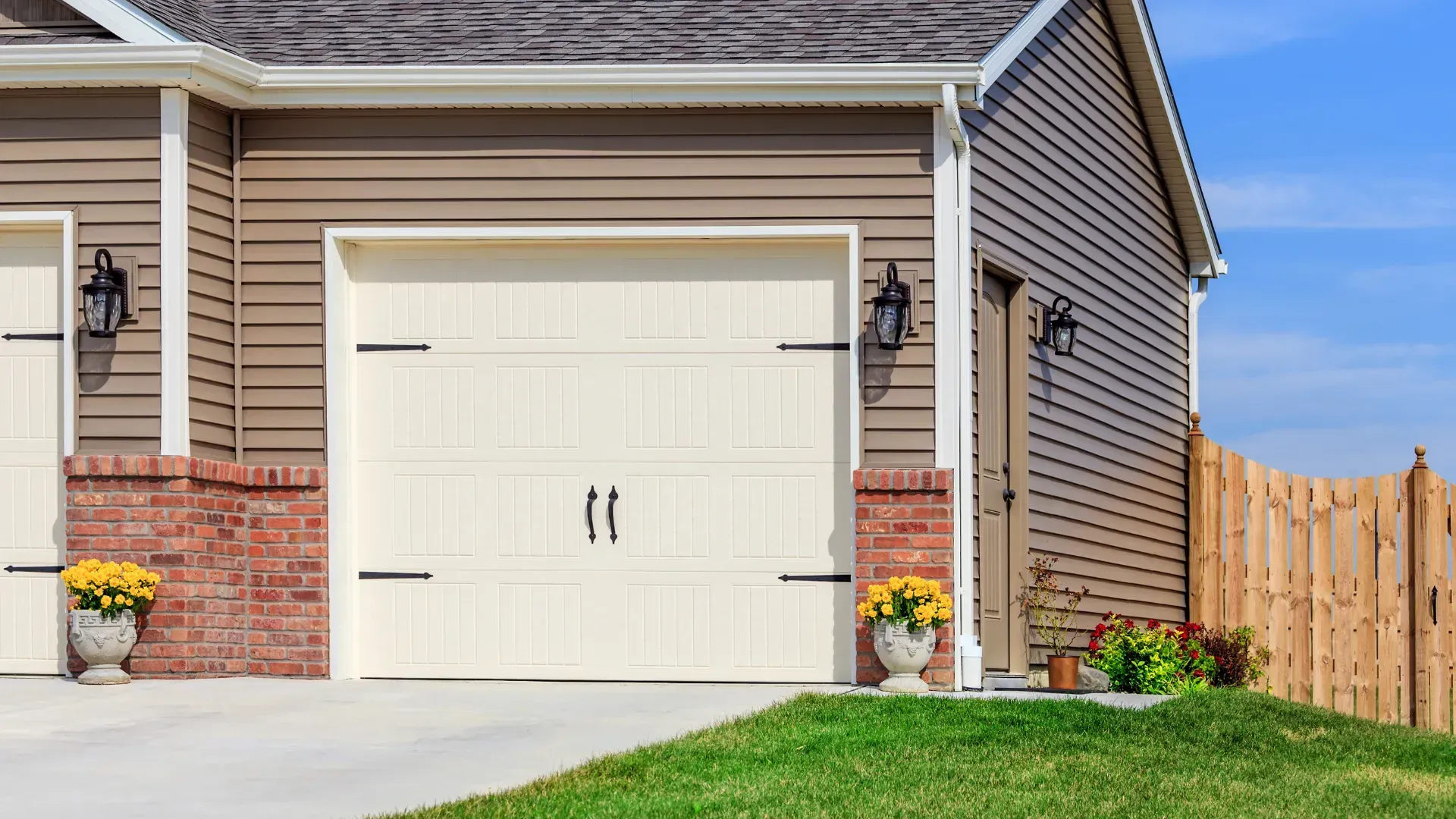 A house with a garage and a wooden fence in front of it.