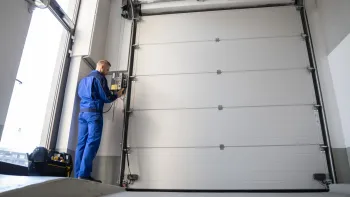 A man is working on a garage door in a garage.