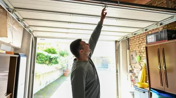 A man is looking up at the ceiling of a garage door.