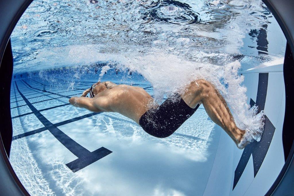 A man is swimming underwater in a swimming pool