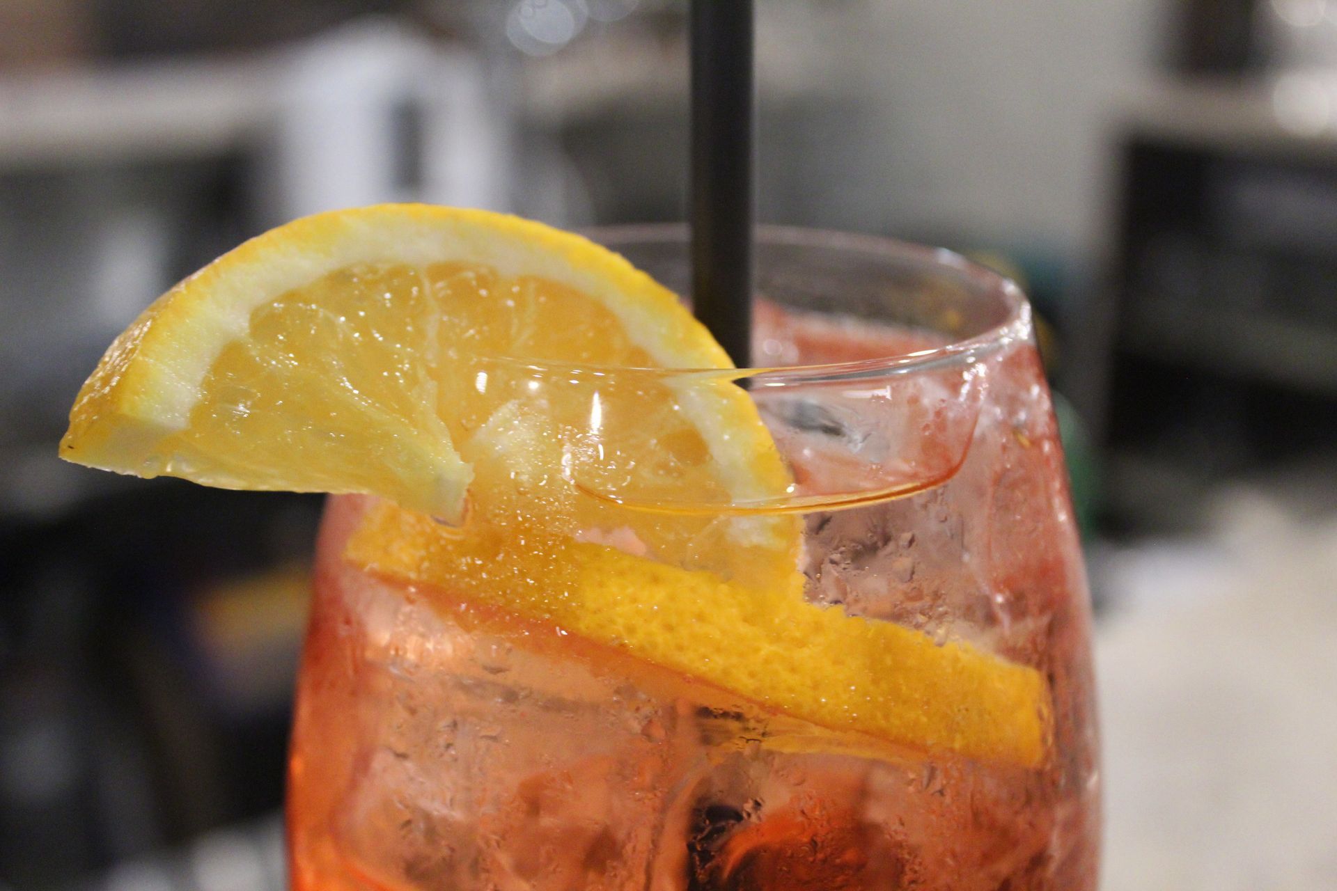 Vino versato in un bicchiere a tavola con del cibo; luce calda e soffusa.