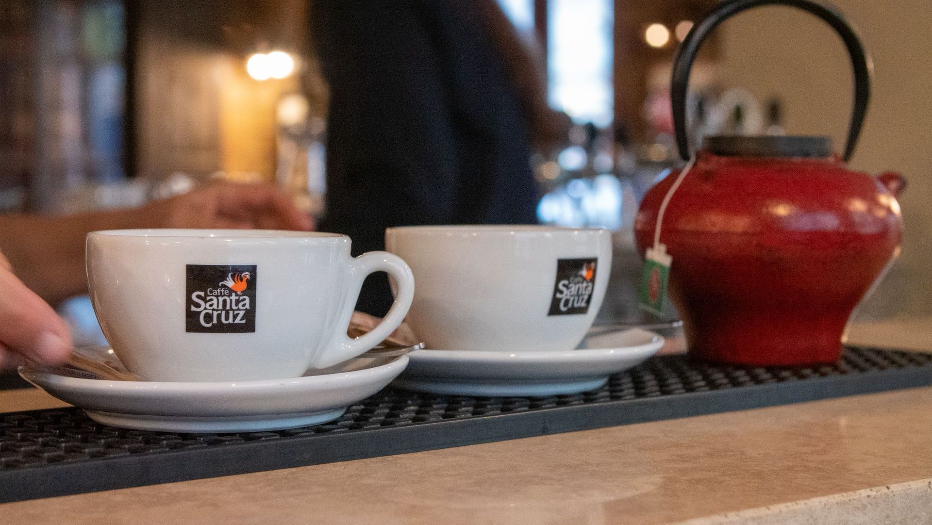 Cappuccino in tazza bianca su piattino, con pasticcini su un piattino, su un tavolo di legno.