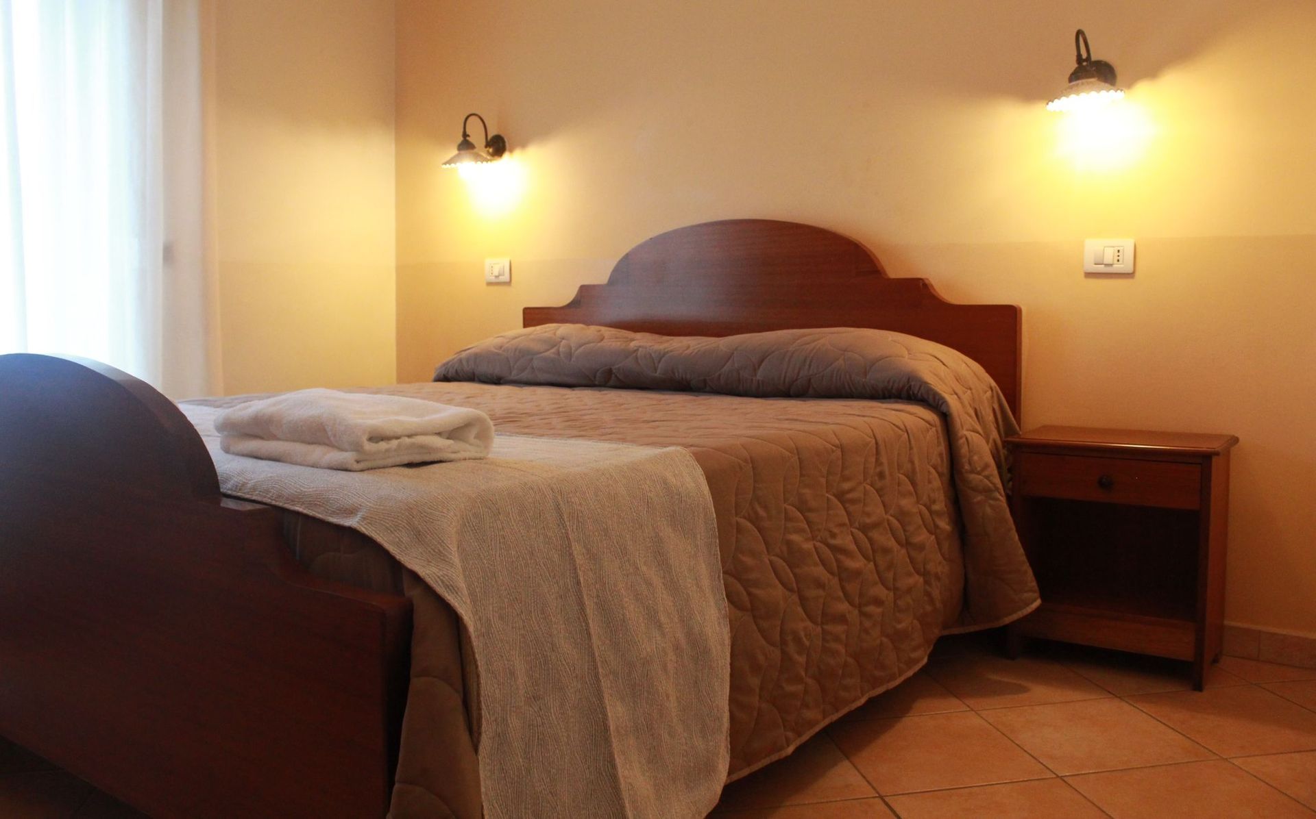 Ingresso del ristorante con porte aperte, tavoli da giardino e luci a ghirlanda, al tramonto.