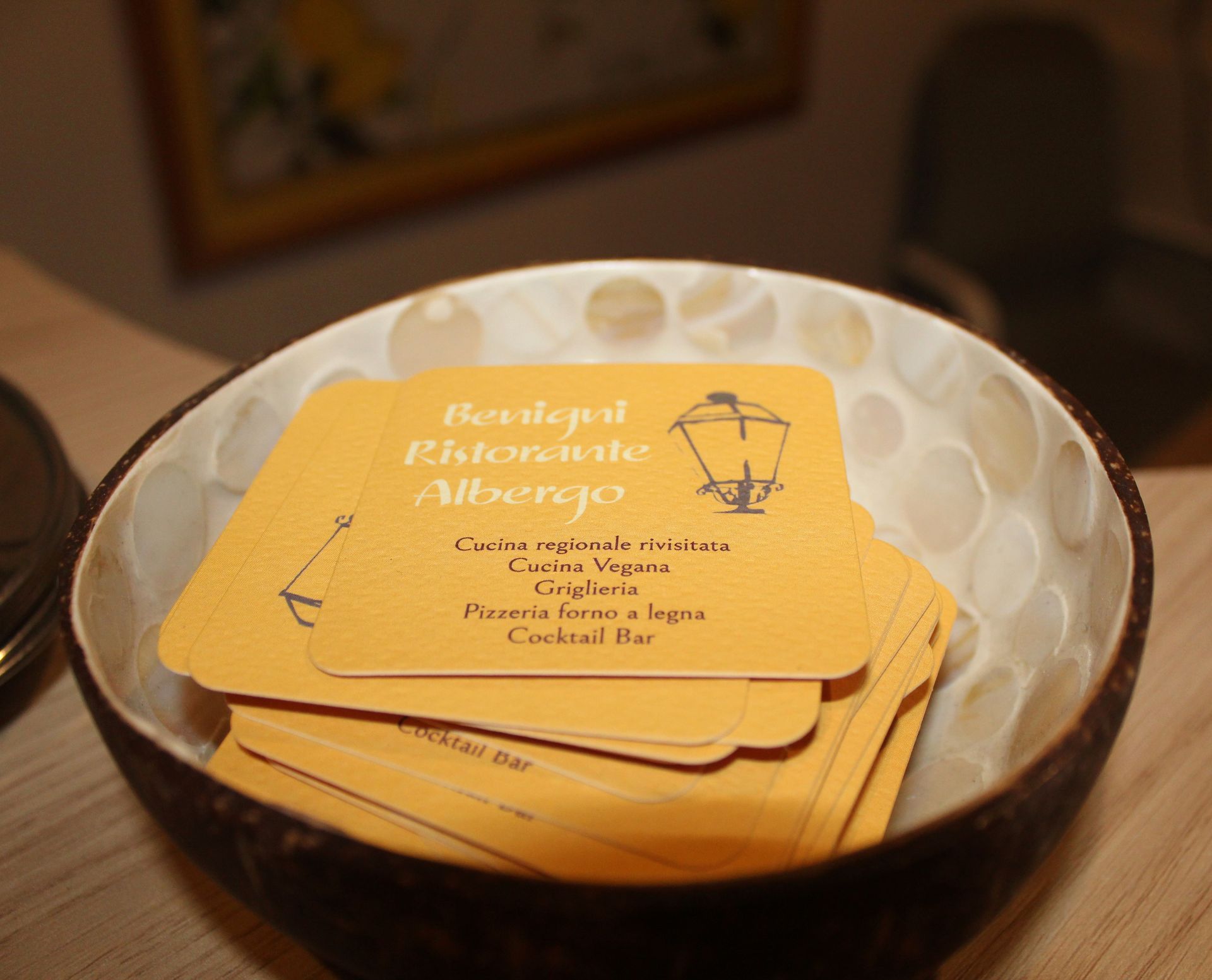 Una ciotola di biglietti da visita gialli per un ristorante, con l'illustrazione di una lampada, su un tavolo.