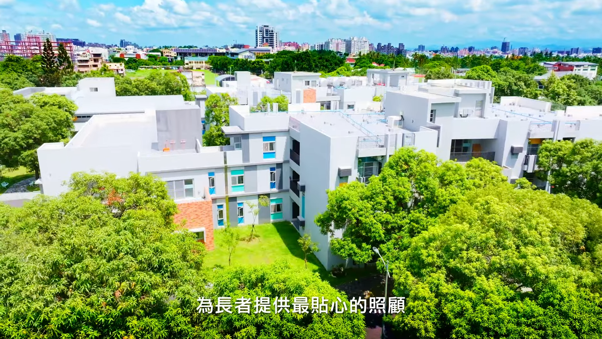 A bright, modern building surrounded by lush green trees under a sunny sky.