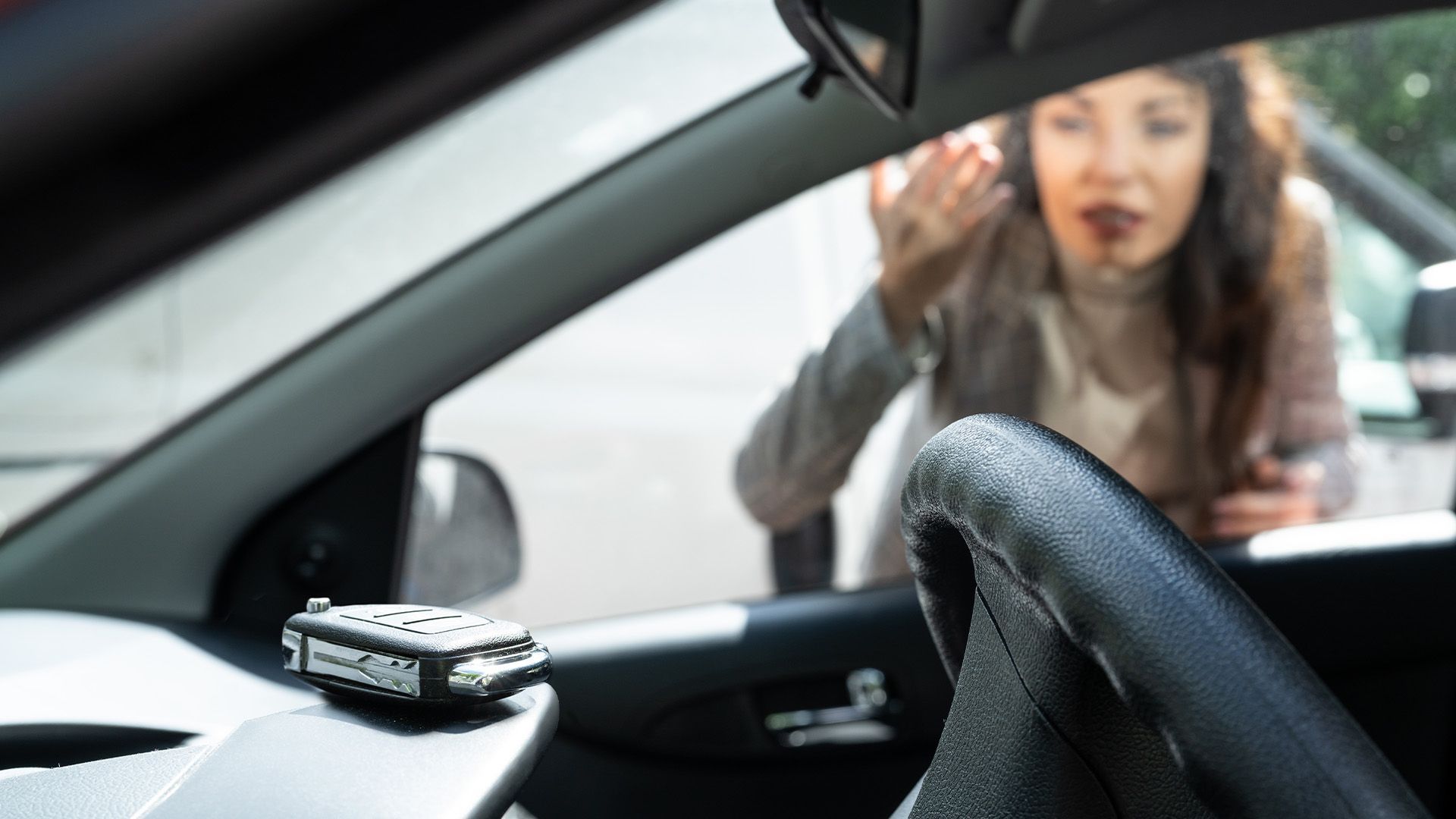 Woman with bloodied face leans into car, reaching out. Dashboard with object visible.