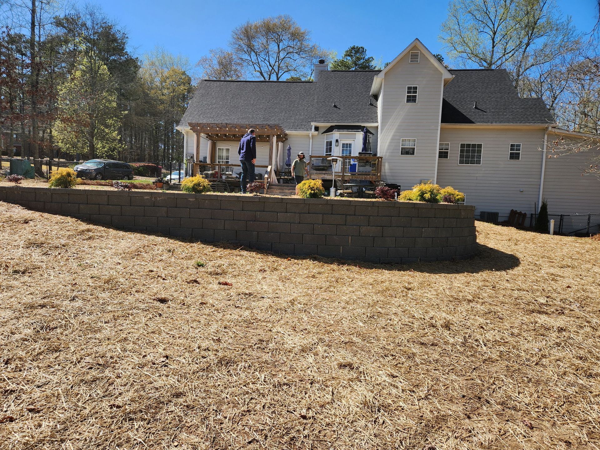 A two-story house with a retaining wall in the yard on a sunny day.