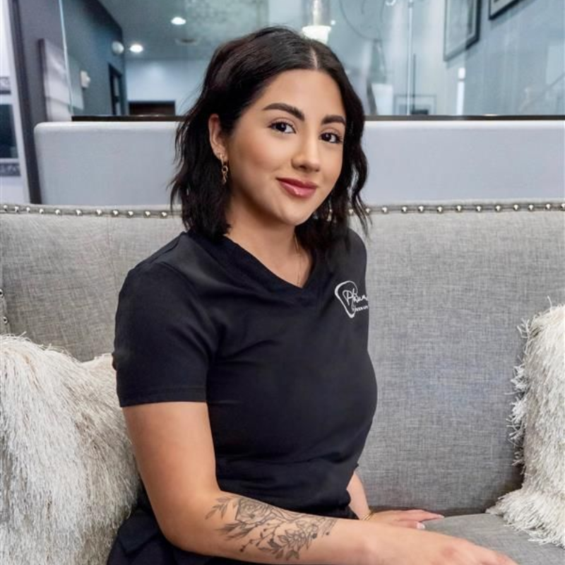 Blonde woman with wavy hair, wearing makeup, looking towards the camera.