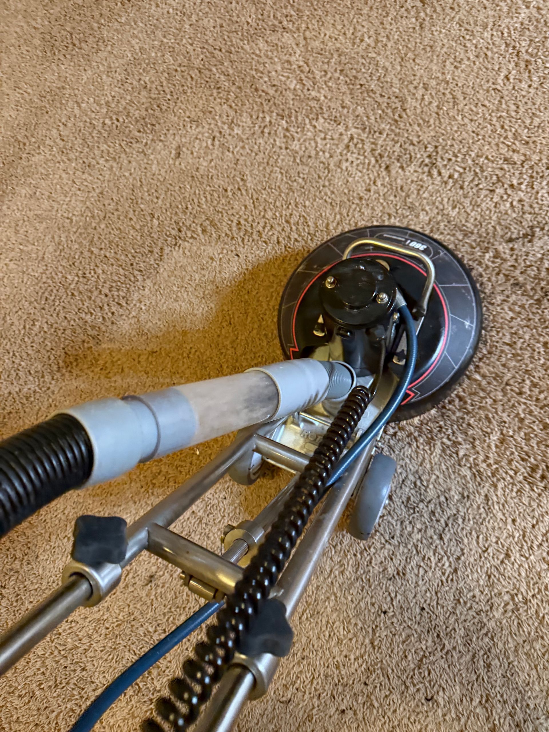 Carpet cleaning machine in use, cleaning beige carpet.