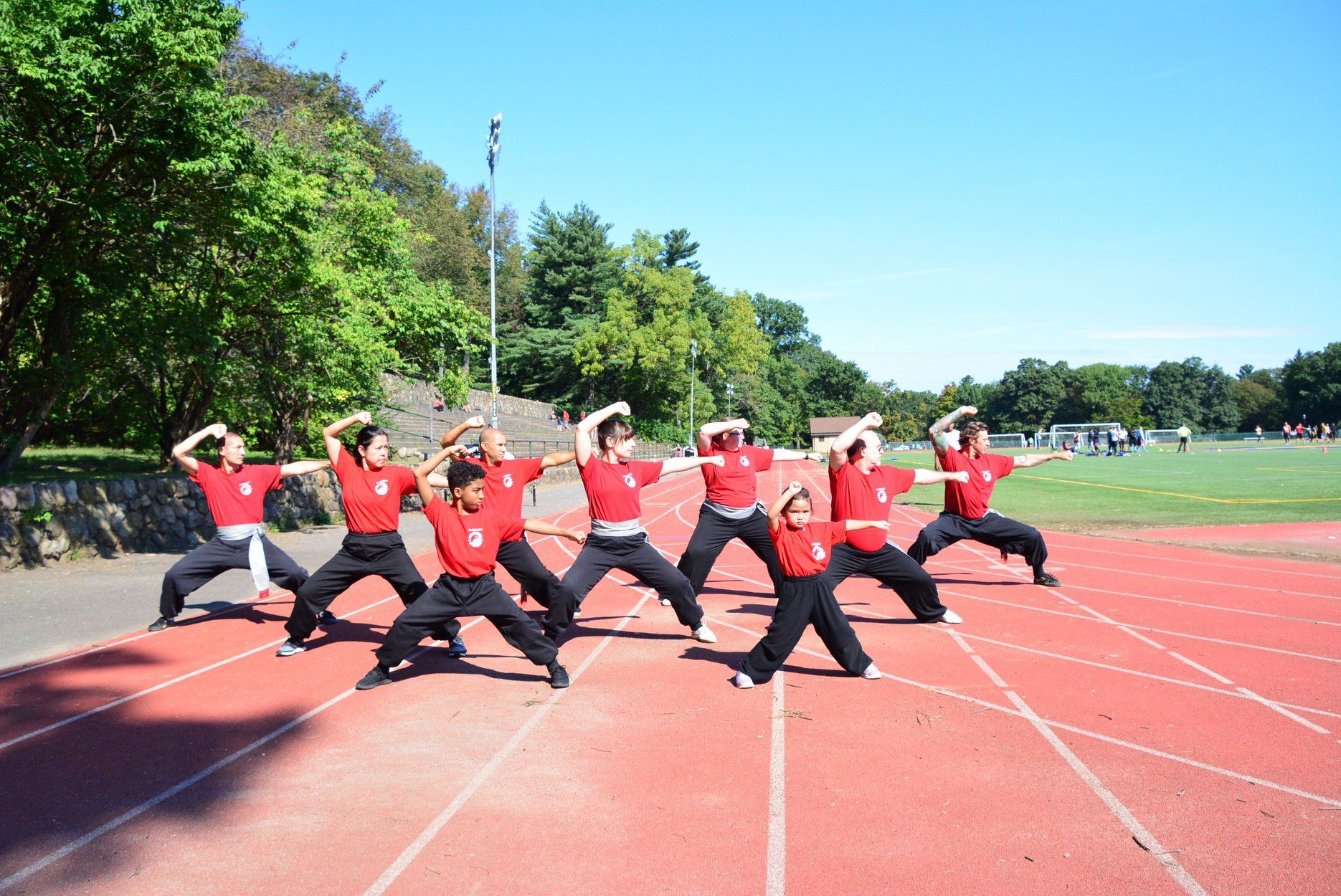 A group of people are practicing martial arts on a track.