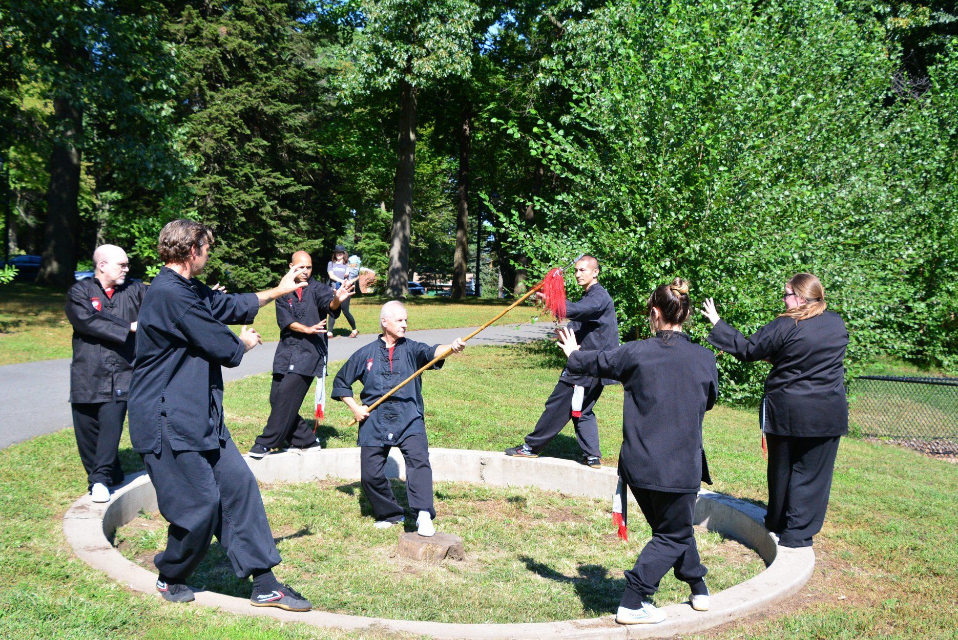 A group of people are practicing martial arts in a park.