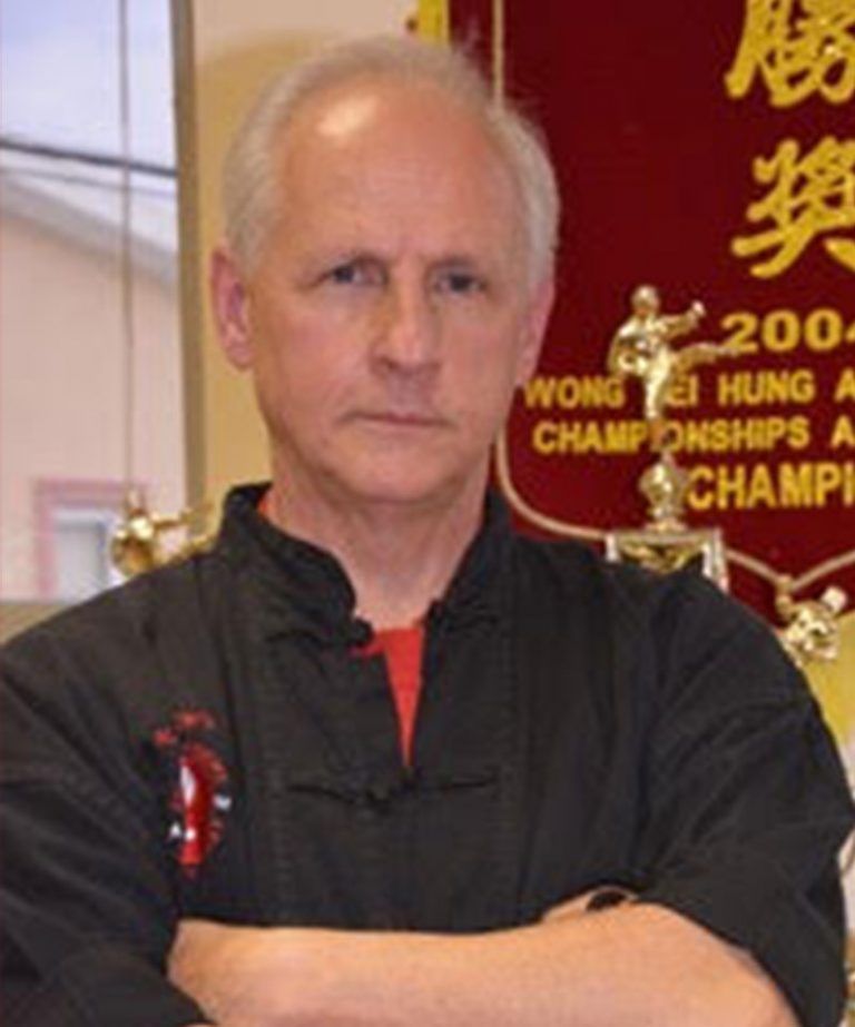 A man with his arms crossed in front of a banner 