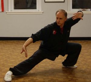 A man is practicing martial arts on a wooden floor
