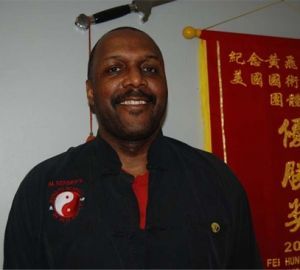 A man stands in front of a red banner with chinese writing on it