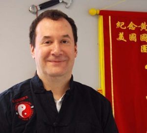 A man stands in front of a red banner with chinese writing on it