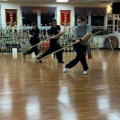A group of people are practicing martial arts on a wooden floor