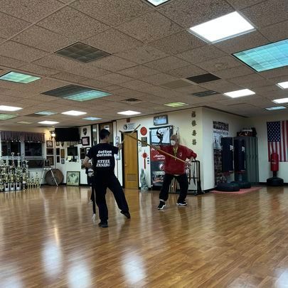Two men are practicing martial arts in a large room