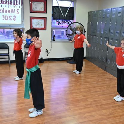 A group of children are standing in a room with lockers.