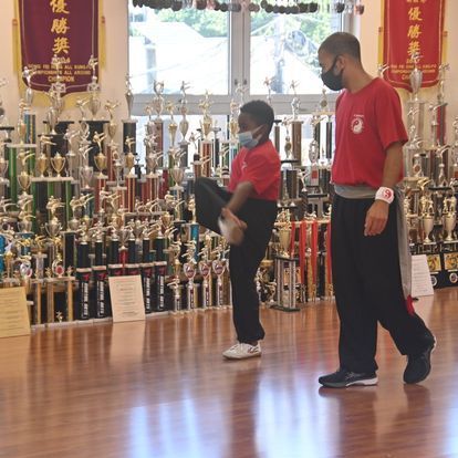 A man and a boy are standing in front of a wall of trophies