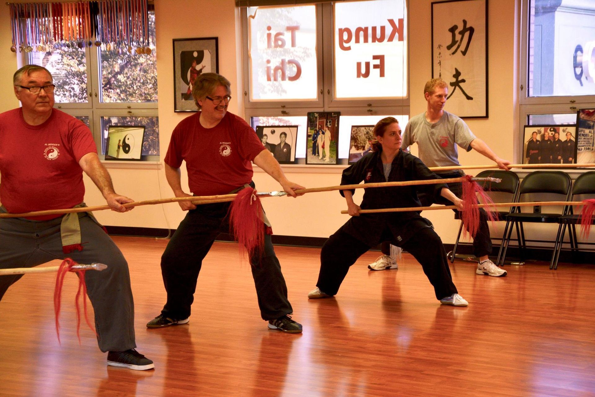 A group of people are practicing martial arts in a room with chinese writing on the wall