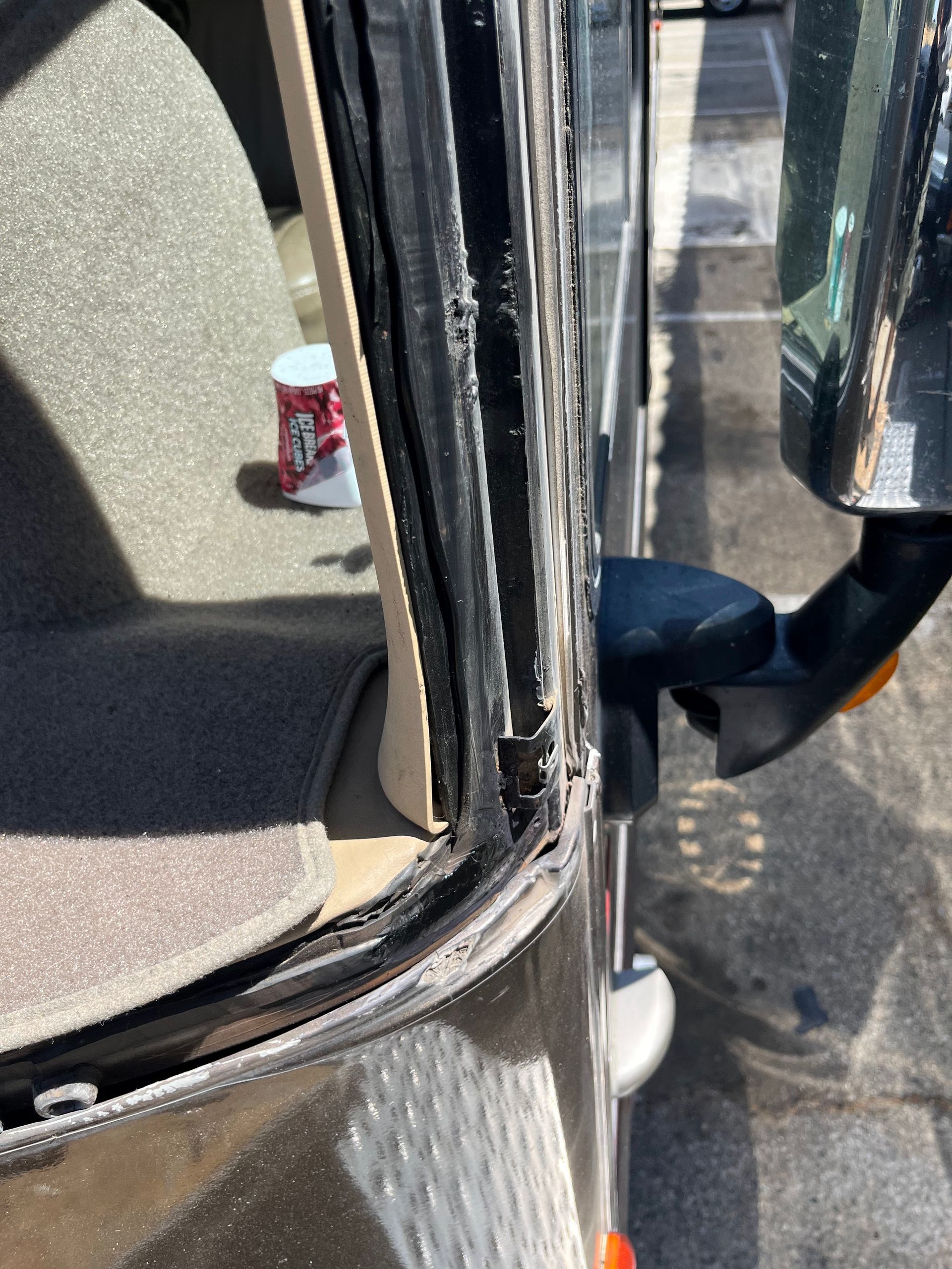 Close-up of a bus doorway with a drink can on the floor near the seat.